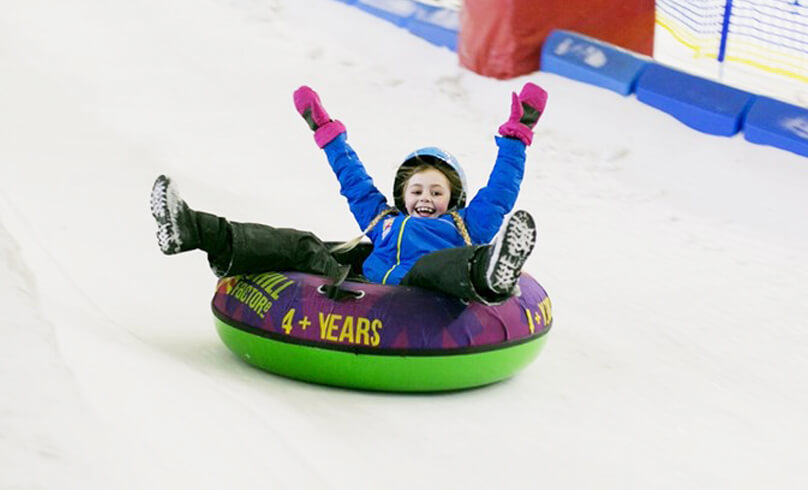 Child going down a ski slope on a slide
